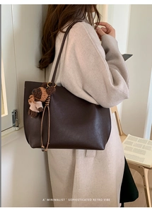 Close-up of deep brown pebbled leather tote bag with a cute striped bear charm detail