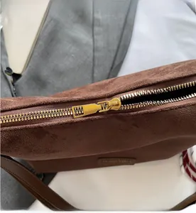 Détail de la fermeture éclair en métal doré sur un sac cabas en daim marron pour femmes