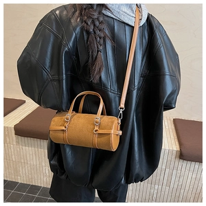 Back view of model wearing a vintage brown suede cylinder crossbody bag with double buckles