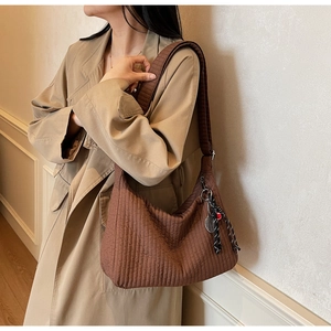 Détail du sac cabas matelassé marron avec large bandoulière et breloque en damier