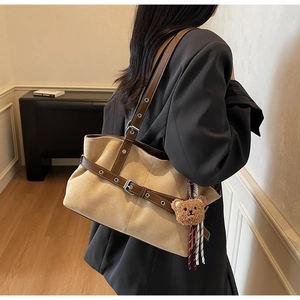 Détail du sac cabas vintage en daim avec lanières en cuir et breloque ours en peluche