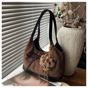 Close-up of brown quilted suede shoulder bag with black leather trim and leopard fur charm