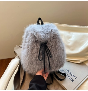 Detail of grey faux fur backpack with black drawstring closure and soft fluffy texture