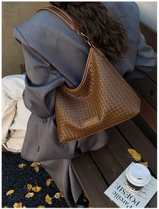 Close-up of a brown woven texture hobo bag with gold metal buckle and leather strap
