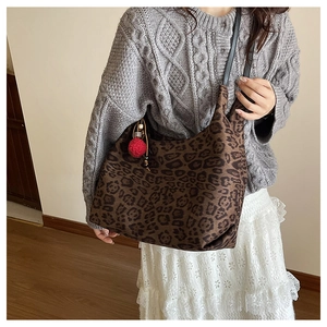 Detail of large leopard print tote bag with black strap and red pompom charm detail