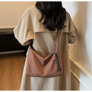 Détail de la texture plissée du sac hobo marron avec pendentif raquette de tennis