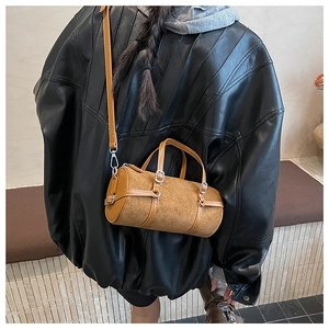 Detail of vintage brown cylinder crossbody bag with suede texture and silver buckles
