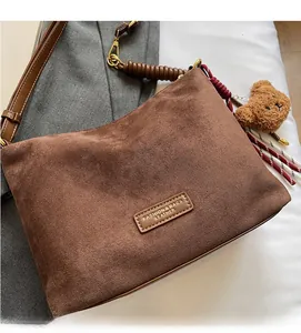Détail du cabas en daim marron avec étiquette en cuir et pendentif ours en peluche