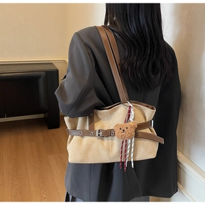 Détail du sac bandoulière en daim vintage avec lanières en cuir et breloque ours