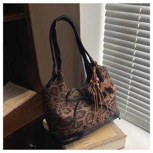 Close-up of leopard print shoulder bag with black leather trim and plush ball charm