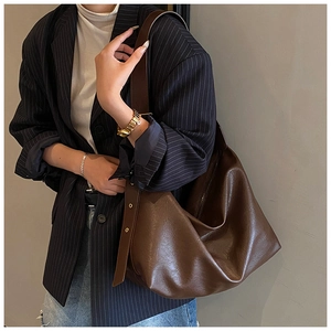 Detail of adjustable strap with metal eyelets on dark brown leather hobo shoulder bag