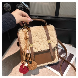 Detail of faux fur and brown leather mini backpack with plush pom-pom charms