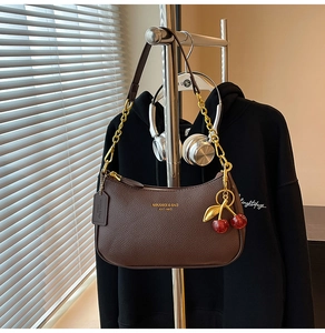 Detail of coffee brown lychee pattern leather crescent bag with chain and cherry charm