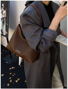Detail of a deep coffee woven leather tote bag shown in a professional autumn street style