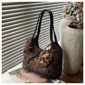 Detail of leopard print handbag with black leather bow and plush charm accessory