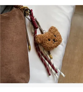 Détail d'un joli charm d'ours en peluche marron avec glands tissés sur le sac