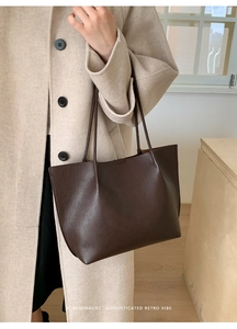 Deep brown pebble leather tote bag shown on shoulder with minimalist retro vibe