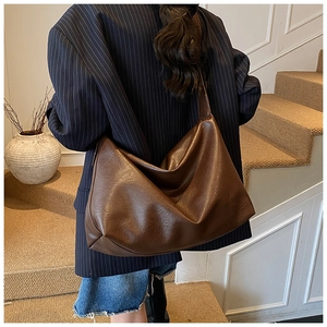 Close-up of soft brown leather hobo bag with vintage texture on model's shoulder