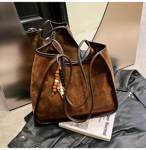 Detail of vintage suede leopard tote bag featuring ethnic bead charm and leather handles