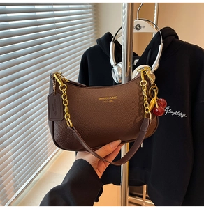 Close-up of brown lychee leather hobo bag with gold chain and cherry charm detail