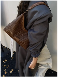 Detail of dark brown woven leather shoulder bag showing texture and adjustable strap
