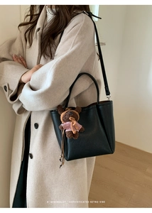 Detail of minimalist black pebbled leather bucket bag with cute teddy bear charm