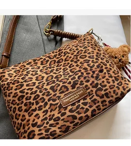 Detail view of leopard print tote featuring soft suede texture and leather trim with bear charm