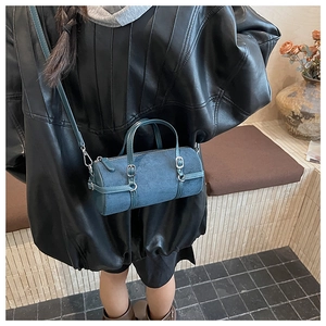 Detail view of retro cylindrical crossbody bag in dark peacock blue suede with silver buckle