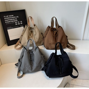 Close-up of four nylon drawstring bucket bags with YOUI BEAR embroidery on display