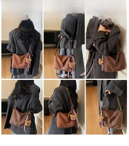 Collage d'un sac hobo en daim marron avec chaîne en métal et charm d'ours mignon