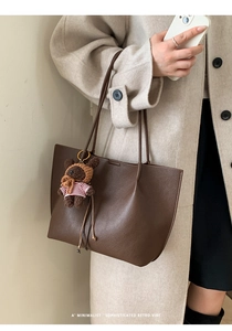Close-up of brown litchi grain tote bag with cute bear charm on a female model