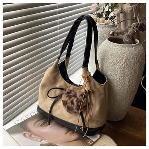 Detail of hobo bucket bag with quilted suede, leather bow, and leopard fur charm