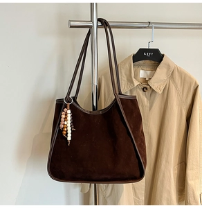 Detailed view of brown suede tote bag with leather piping and decorative ethnic beads