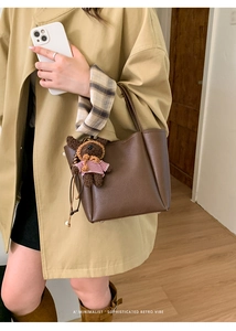 Close-up of brown pebbled leather handbag with a cute teddy bear plush charm detail
