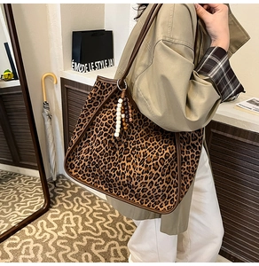 Detail of leopard print tote bag with wooden bead pendant and brown edge stitching