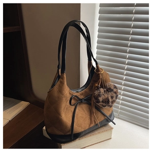 Detail of suede hobo bag featuring quilted patterns, black bow, and leopard heart charm
