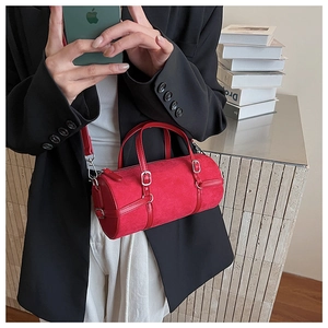 Detail of red cylinder barrel bag with suede texture and silver hardware on a model