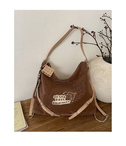 Close-up of leopard print shoulder bag with bear embroidery and biscuit charm detail