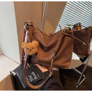 Détail du sac cabas en daim marron avec écusson en cuir et breloque ours en peluche mignonne