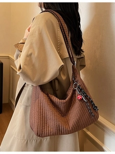 Grand sac cabas matelassé marron avec breloques vu de côté sur un mannequin