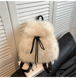 Close-up of fluffy off-white plush backpack with black drawstring and soft faux fur texture