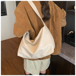 Model view of an off-white soft leather hobo bag with wide shoulder strap design