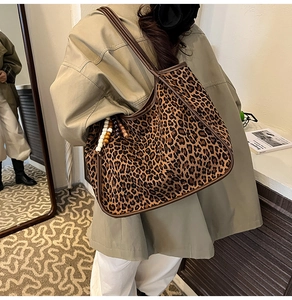 Detail of leopard print tote bag with beaded tassel charm and brown leather straps