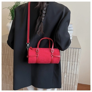Detail of red cylindrical shoulder bag with velvet texture and silver metal hardware