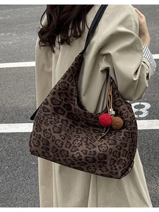 Retro leopard print tote bag with plush charms worn on shoulder over trench coat