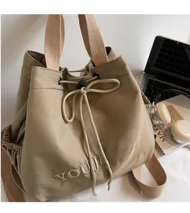 Detail of khaki drawstring bucket bag showing textured fabric and YOUJI BEAR embroidery