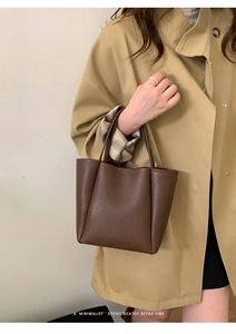 Detail of minimalist dark brown litchi textured leather tote bag on model