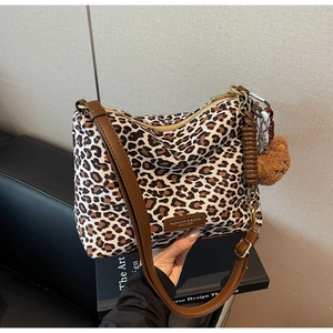 Detail of leopard print tote bag with brown leather strap and plush bear charm