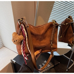 Détail du sac cabas en daim marron avec pendentif ours et logo mode embossé