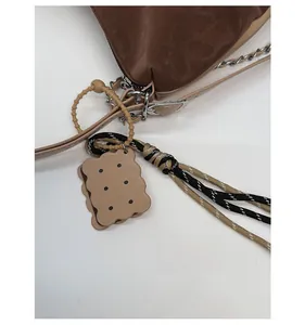 Detail of cute biscuit charm and woven rope on brown leopard print shoulder bag